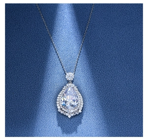 Macro shot of silver teardrop pendant necklace featuring pear-cut main stone and halo accents