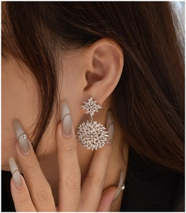 Close-up of sparkling snowflake earrings with rectangular crystal stones on a model