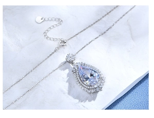 Macro shot of silver pear-shaped pendant necklace with double-layer halo of small diamonds