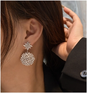 Detailed view of silver snowflake earrings with cubic zirconia on a model's ear