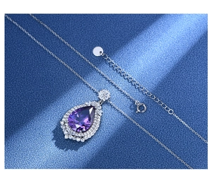 Close-up of a pear-shaped purple gemstone pendant with a halo of white pavé stones