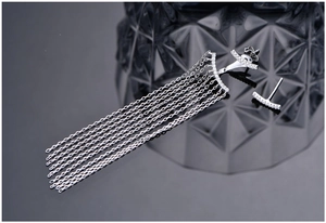 Detail of silver long tassel earrings with sparkling zircons on a dark background