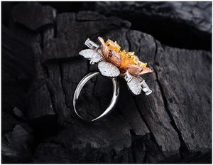Macro detail of tricolor gold floral ring with micro-pave zircons on black charcoal texture