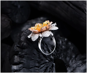 Macro shot of tricolor flower ring with micro-pave zircons on textured black charcoal