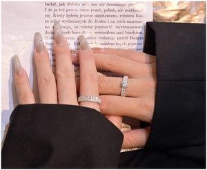 Close-up of 925 silver bridal set rings with cubic zirconia worn by model over a book