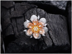 Macro detail of pavé-set flower ring featuring dual-tone layered petals on black charcoal