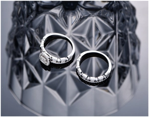Macro shot of silver halo ring set with cubic zirconia stones on dark glass background