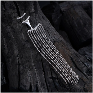 Macro view of long silver tassel earrings with crystal pave detailing on charcoal wood