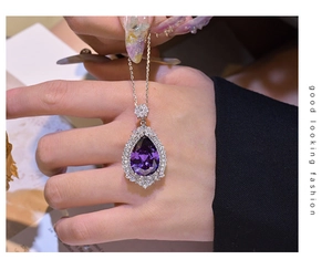 Close-up of a purple pear-shaped gemstone pendant with white zircon halo on a silver chain