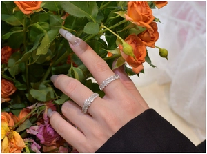 Close-up of stacked S925 silver wave rings with zircon inlays worn by a model