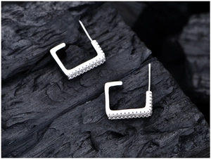 Macro detail of square S925 sterling silver earrings with inlaid rows of zircon stones