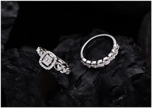 Macro shot of silver cluster ring and pave band against black charcoal background