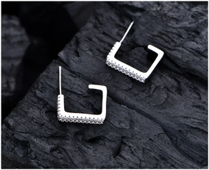 Detailed close-up of square silver hoop earrings with sparkling micro-pave zircon stones