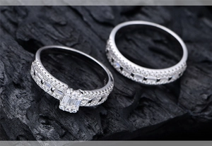 Detailed macro shot of an emerald-cut silver ring set with micro-pave diamonds on black charcoal