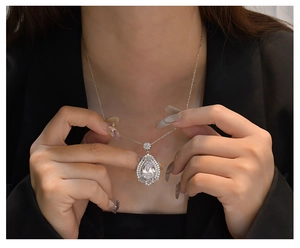 Macro detail of pear-shaped pendant necklace with double halo diamonds on model