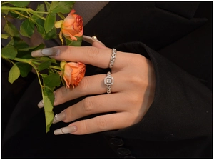 Macro shot of S925 silver twist ring and square cut diamond ring on a hand