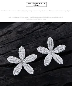 Détail macro de boucles d'oreilles fleur en argent 925 avec zircons 5A sur bois