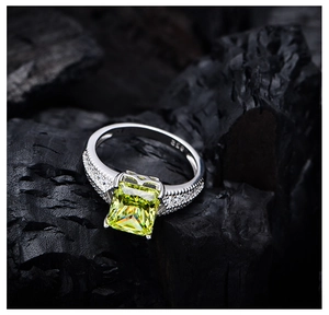 Nahaufnahme eines Rings aus 925er Sterlingsilber mit großem grünem Edelstein auf Holzkohle
