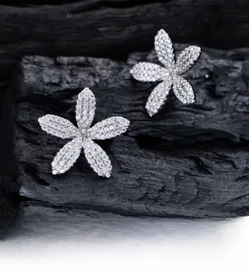 Vue macro de boucles d'oreilles fleur en argent avec zircons blancs sur bois sombre