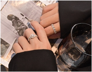 Close-up of stacked S925 silver rings with square halo stone on a model hand