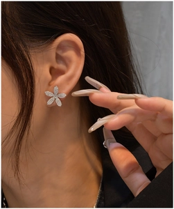 Gros plan de boucles d'oreilles fleurs serties de zircons brillants portées à l'oreille
