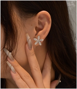 Détail de boucles d'oreilles fleur argentées avec cristaux micro-pavés sur un modèle