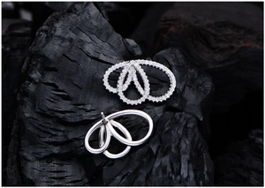 Détail macro de boucles d'oreilles géométriques en argent avec pavage de zircons blancs