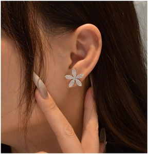 Gros plan sur une boucle d'oreille fleur à cinq pétales avec cristaux micro-pavé sur l'oreille