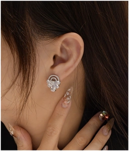Macro shot of S925 silver stud earring with pear-cut zircon crystals on a female model