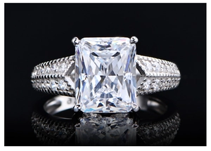 Makro-Detail von Aquamarin-Ring mit Radiant-Schliff und Pavé-Diamantband auf Schwarz