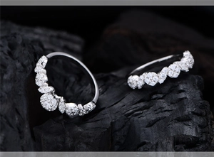 Detail of two S925 silver micro-pave wedding rings set on black textured stone