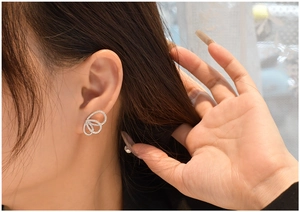 Gros plan de boucles d'oreilles ovales argentées superposées serties de micro-diamants