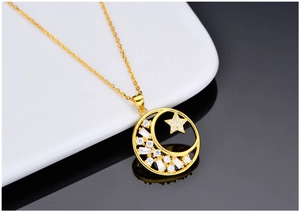 Detail of gold star and moon pendant with white zircons on a delicate cable chain