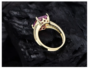 Macro shot of 14k gold plated ring with ice cut rectangular pink gem on dark rock
