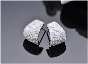 Macro shot of silver J-shape stud earrings with micro-pave white zircon on black mirror