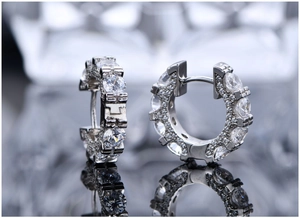 Macro shot of silver hoop earrings with round zircons and decorative T-shaped side structure