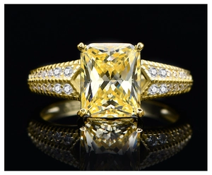Macro shot of yellow cushion cut gemstone ring with diamond pavé on gold band