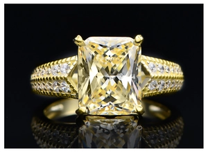 Macro shot of 5.6ct radiant cut yellow gemstone ring on a reflective black background