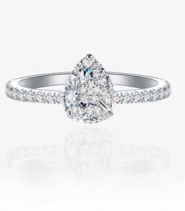 Macro shot of silver engagement ring with pear-cut main stone and pavé-set side diamonds