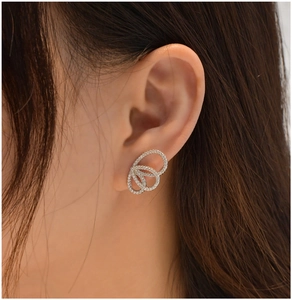 Gros plan de boucles d'oreilles anneaux entrelacés en argent sertis de cristaux brillants