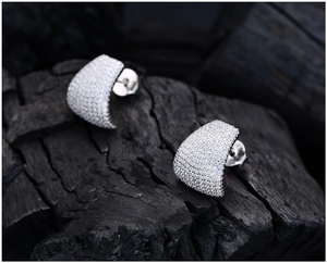 Macro shot of S925 hallmark on silver pavé earrings against dark textured background