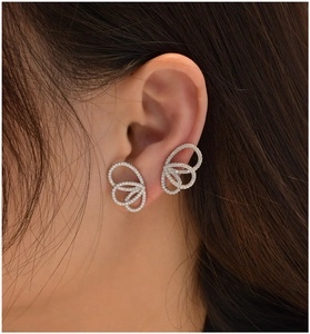 Détail de boucles d'oreilles ailes de papillon en cristaux portées pour un look scintillant