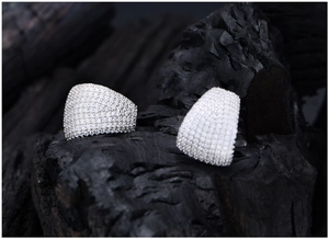 Detailed macro view of wide micro-pave silver earrings with white cubic zirconia stones