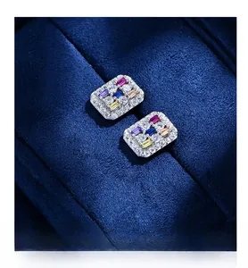 Macro shot of rectangular silver earrings featuring colorful zircon stones on velvet