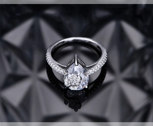 Macro view of pear-cut zircon ring with floral cluster accents on polished silver band