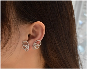 Gros plan détaillé des boucles d'oreilles ailes de papillon argentées et cristaux blancs