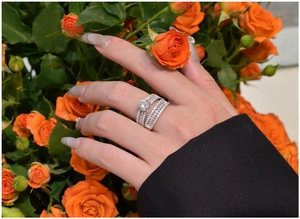 Detailed view of luxury S925 silver wedding ring set on hand with orange roses background