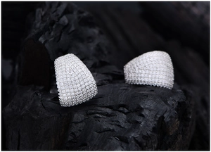 Macro detail of 925 sterling silver pave stud earrings on a dark textured rock