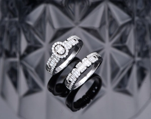 Detail of oval-cut zircon main ring and baguette-set wedding band on glossy black surface