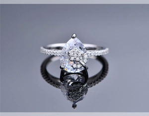 Macro shot of pear-cut diamond ring featuring a delicate flower detail and pavé band